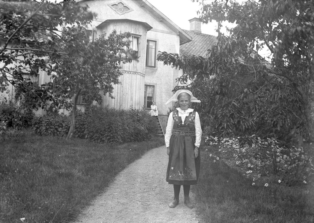 The girl in the beautiful Sweden suit is not certain identified yet. But the photo was taken outside the State Building in Hästeryd, Frinnaryd 1915.