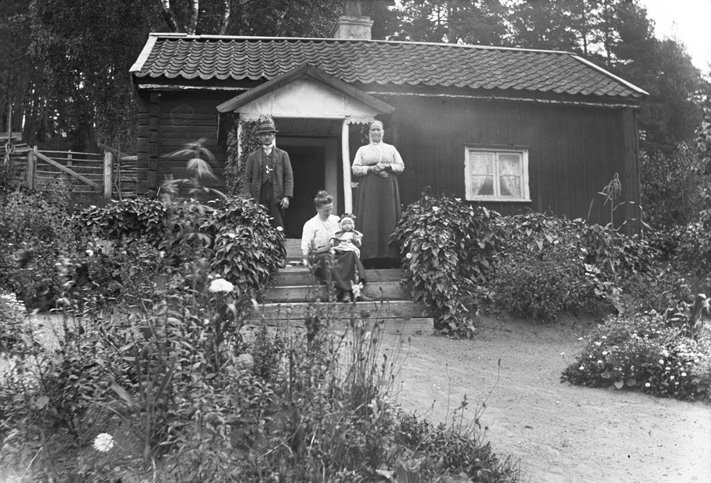 Rakelt, Vrångsjö 1913. Rakelt or Peraklet was a cottage in Vrångsjö manor in Marbäck. The picture shows torparparet Gustav Engdahl (b. 1850) and Augusta Engdahl (b. 1848) and their daughter Esther Engdahl (b. 1888) and her daughter Marta Linnea Ingegerd (b. 1913).