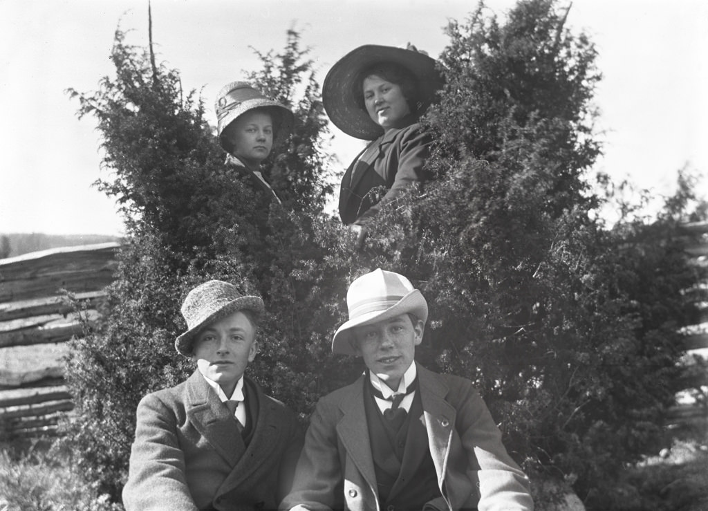 Two in front and two behind the junipers. The women in the background is Carola Aurell and Maria Andersson. The young man on the left is called Henning Aurell and is the brother of Carol Aurell. The man on the right is not yet identified.