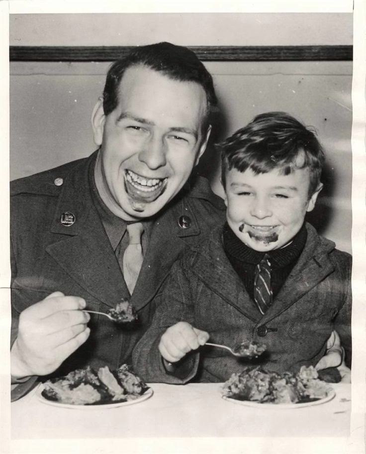 U.S. soldier eating ice cream with a little British boy at Christmas party given by troops of the USAAF Service Command for 100 English evacuees at a station "somewhere" in England, 1943.