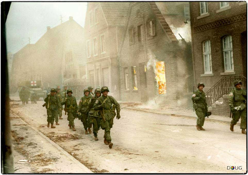 Troops of the 17th U.S. Airborne Division, First Allied Airborne Army, march past a blazing building in Appelhülsen, Germany, as they advance toward the city of Münster, nine miles to the northeast.