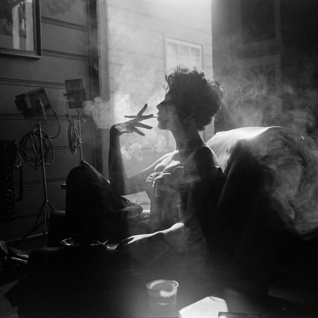 Rita Morena smoking a cigarette during a studio shoot, Hollywood, 1954.