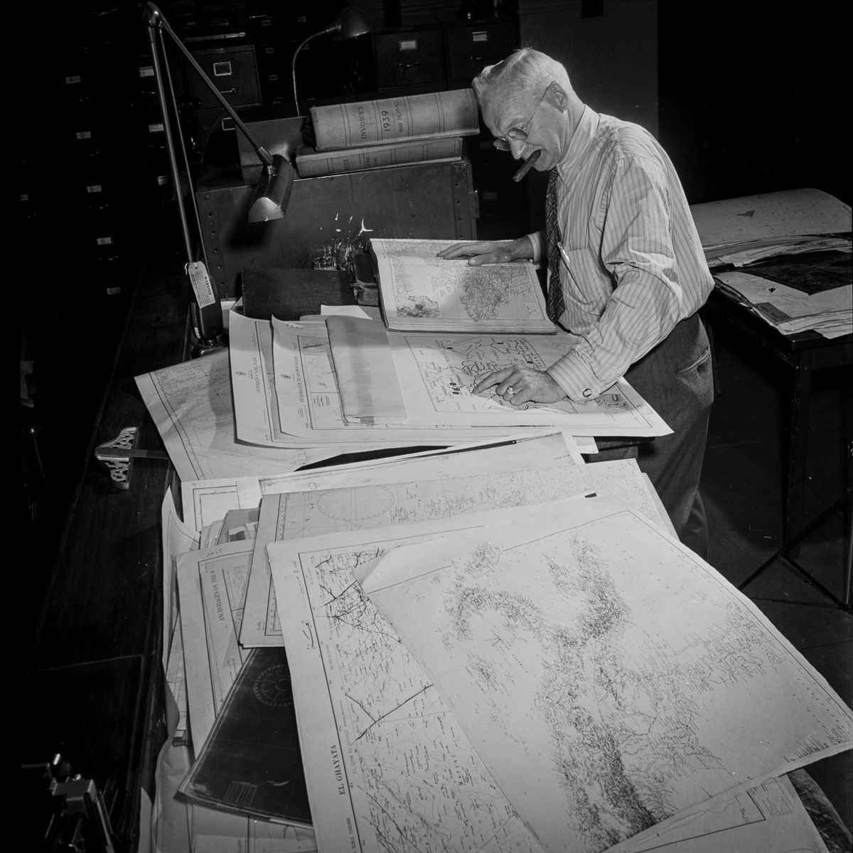 In the art department, the cartographer consults charts to prepare a map of the war in Europe. This employee was also here for the First World War.