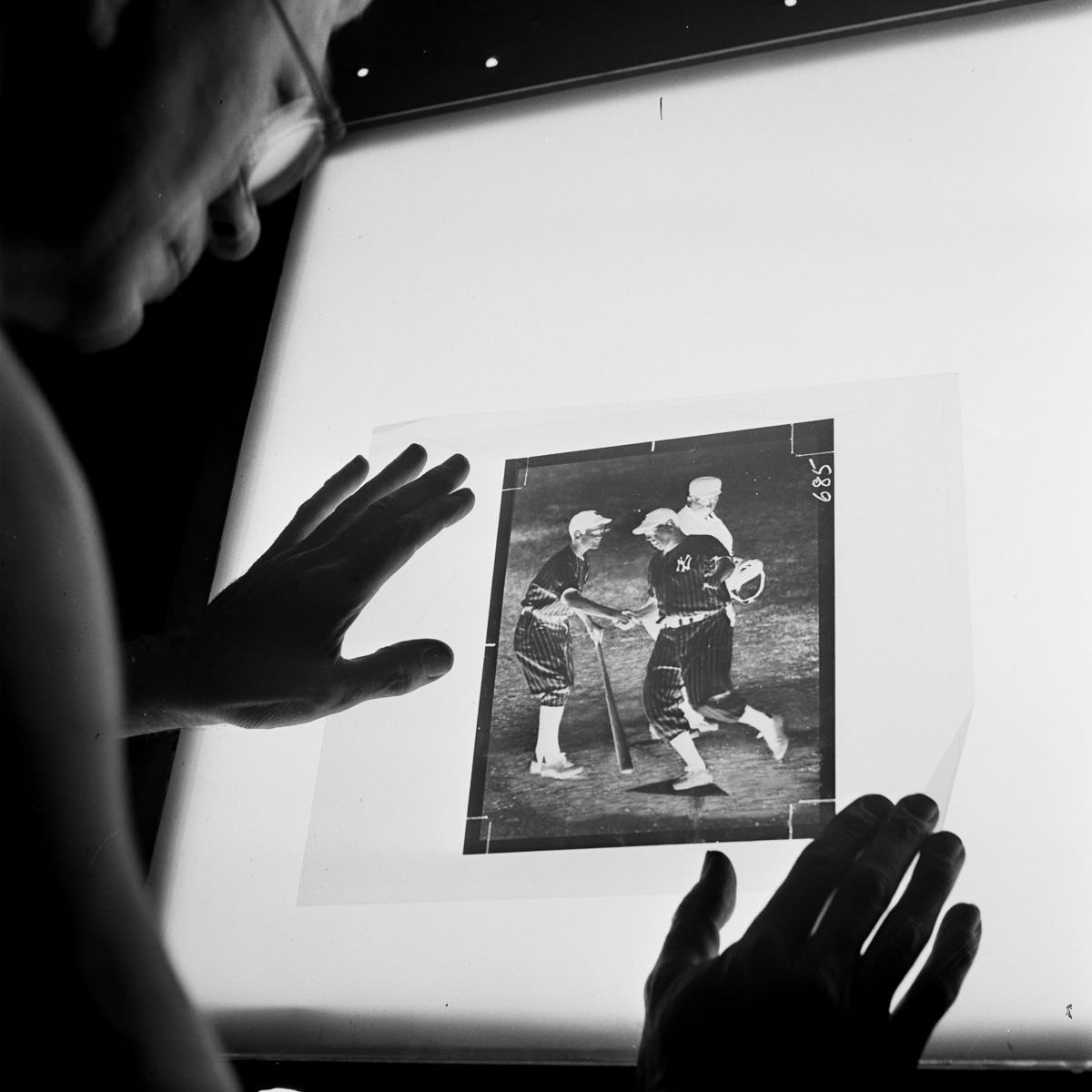 A darkroom technician inspects the dots on the screen of a strip negative before it is transferred to a zinc plate.