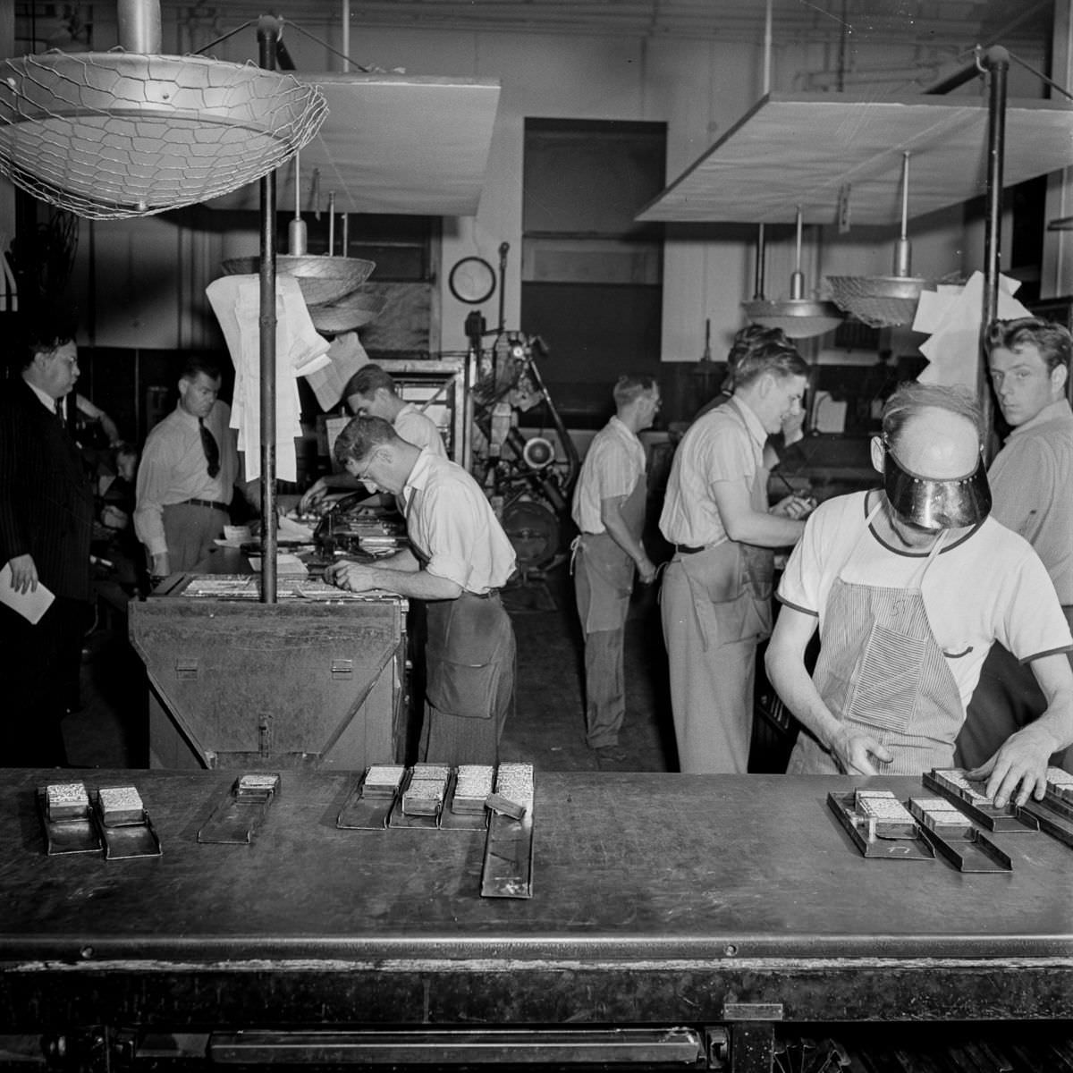 Make-up men pick up linotype slugs from the center table.