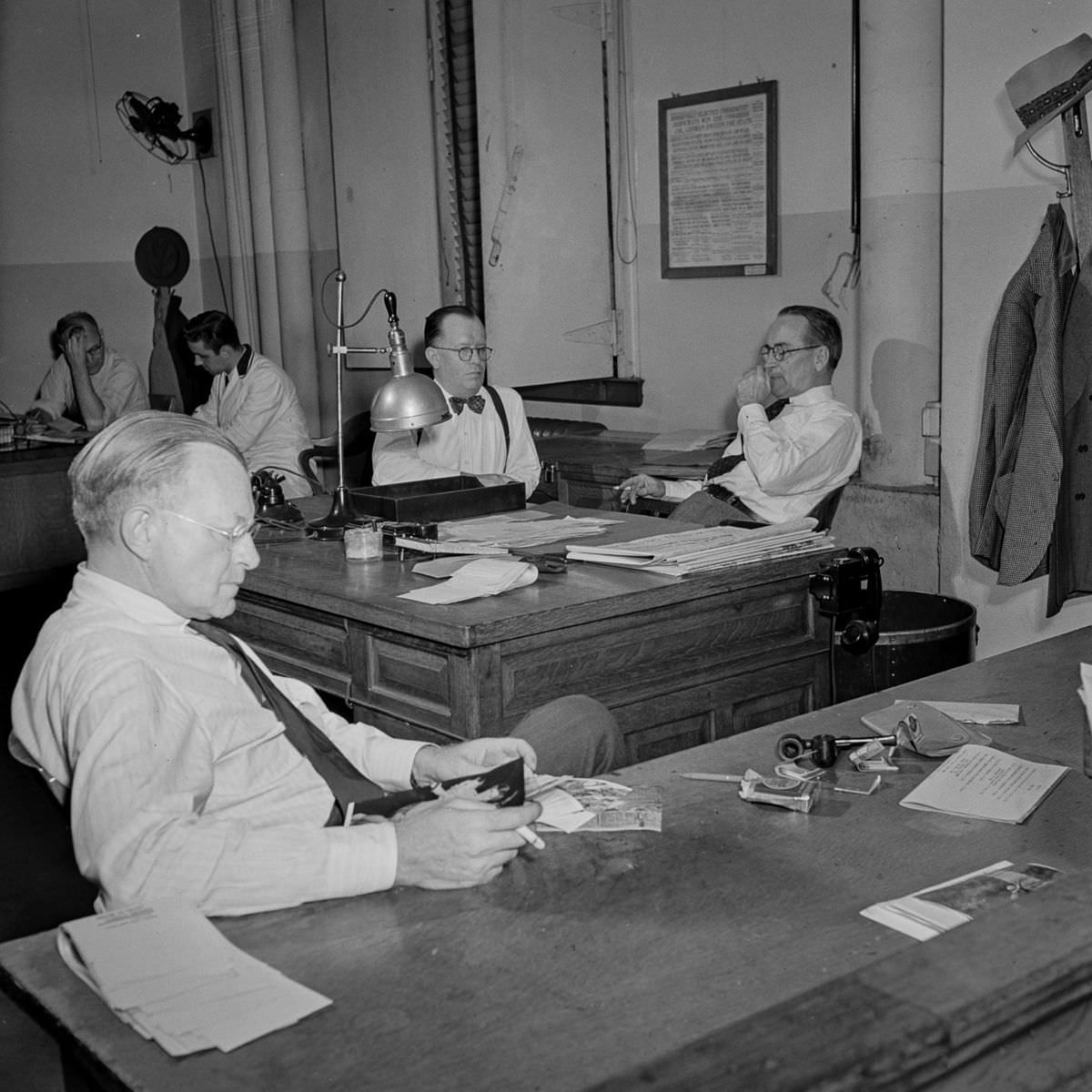 In the bullpen: the assistant managing editor sits in the foreground while the managing editor and night managing editor confer in the background.