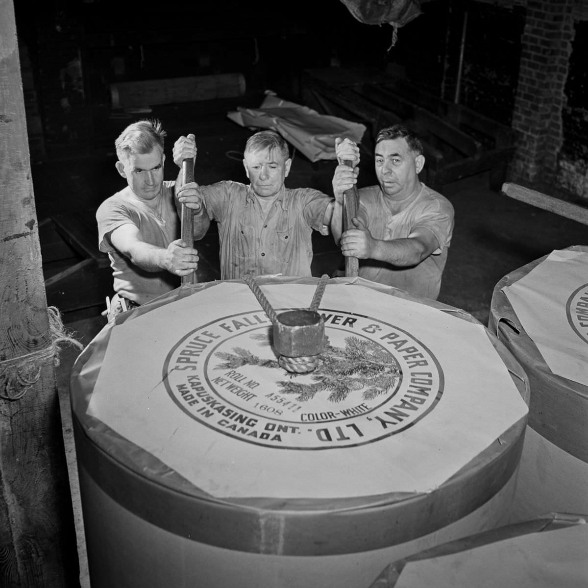 In the reel room, pressmen transport a 1608-pound paper reel to the presses. The reel has enough for about 1300 newspapers.