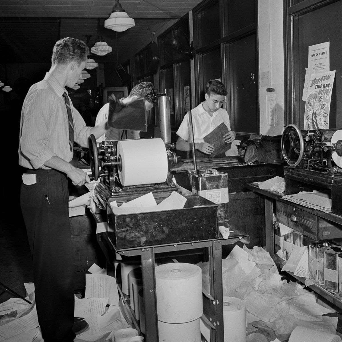 Copy boys mimeograph the dispatches from the telegraphs and pass them through a slot to the newsroom, where they are sorted and distributed to the various desks.