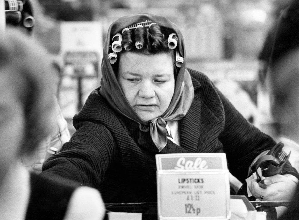 A woman wearing curlers in her hair enjoying shopping in the sales after Christmas, Liverpool, 1974.