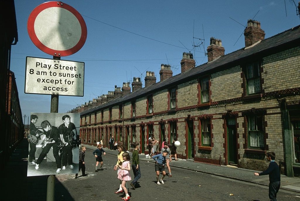 A small Beatles poster hangs on the traffic sign marking a street that is reserved for playing children during the day.