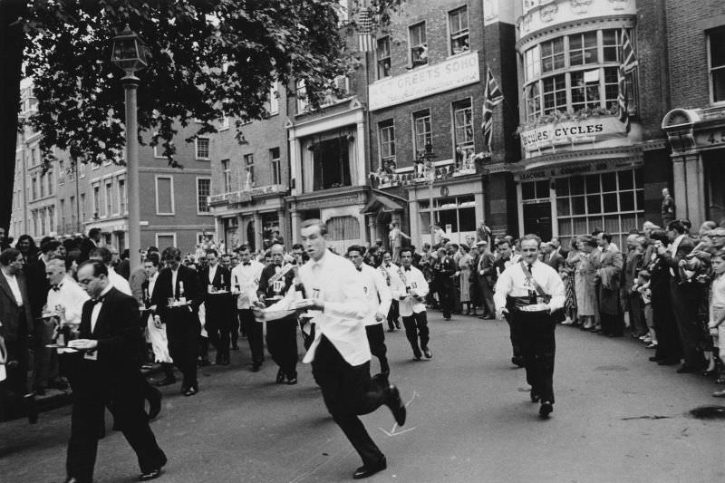 Waiters carrying half bottles of champagne setting off on the annual waiters' race from Soho Square to Greek Street, 1955.