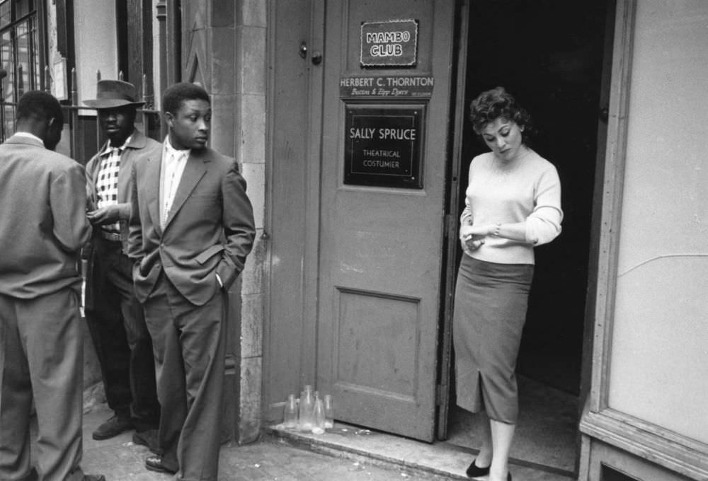 Andria Loran, a model in London’s Soho, democratically elected ‘Queen of Soho 1956’, stands in the doorway of the Mambo Club.