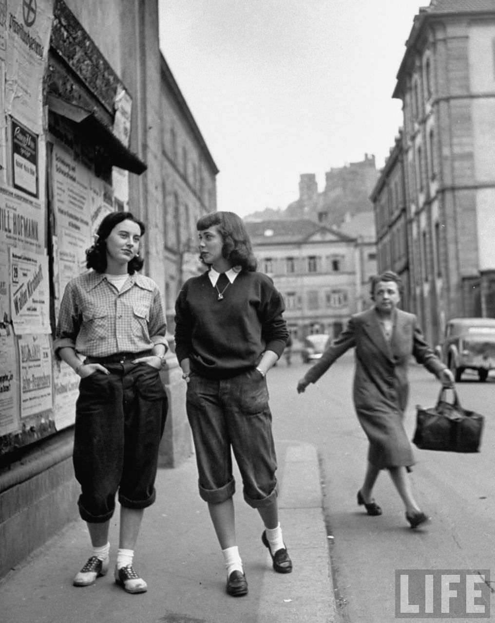 Two American students sauntering along a Heidelberg street, cause staid German women to look at them in wonderment.