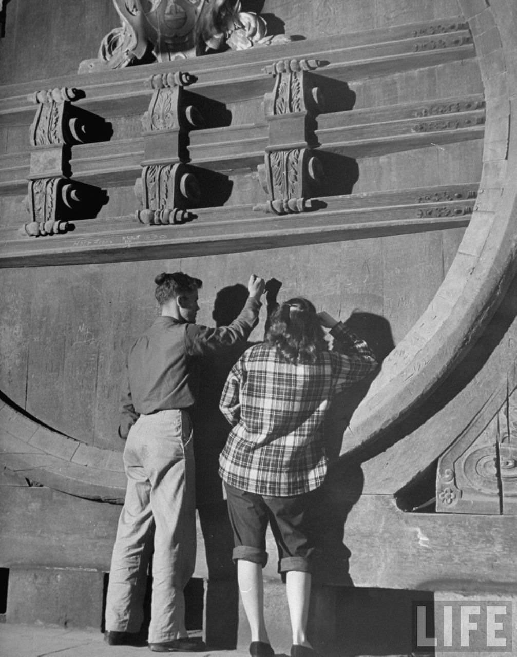 Carving their names on huge wine vatin cellar of Heidelberg Schloss.