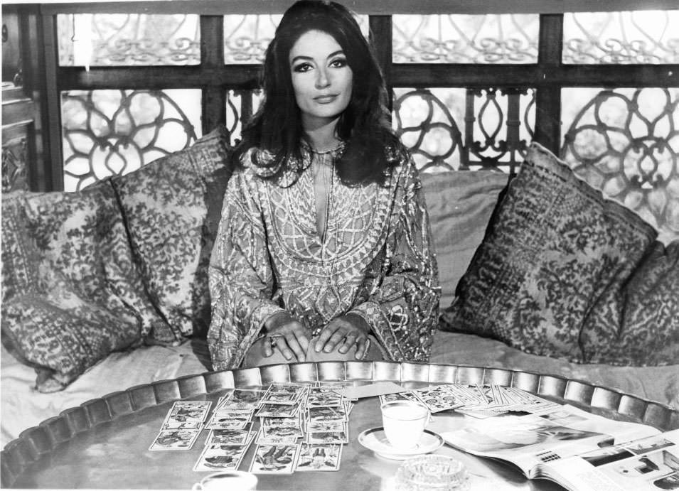 Anouk Aimee sitting before table full of cards in a scene from the film 'Justine', 1969.