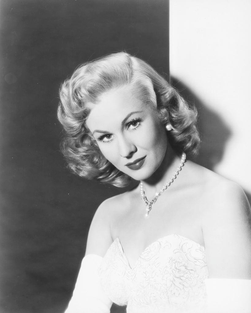 Virginia Mayo wearing white shoulderless dress with a diamond necklace ...