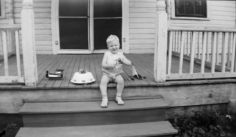 Smiling boy sitting on wooden steps and patio with various toys