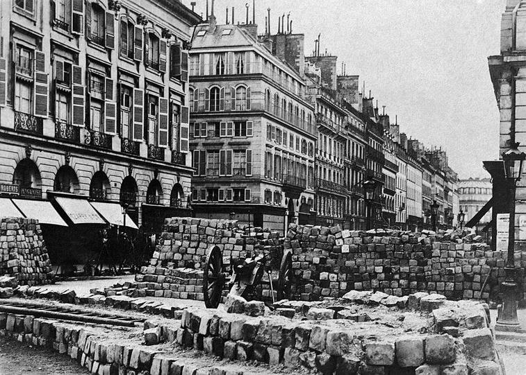 A Paris street is barricaded with a stone-block wall and cannon, during the Franco-Prussian War.