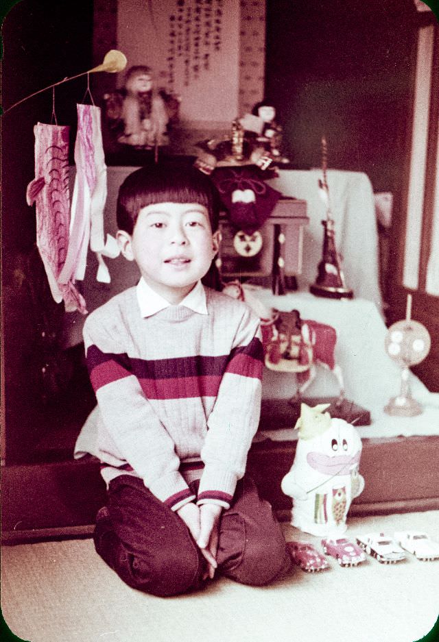 Boy with toy cars and a carp streamer sitting in a room
