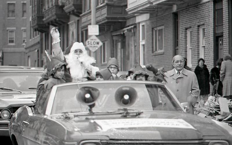 Santa Claus in car with children dressed as elves at North End Christmas Party and Parade