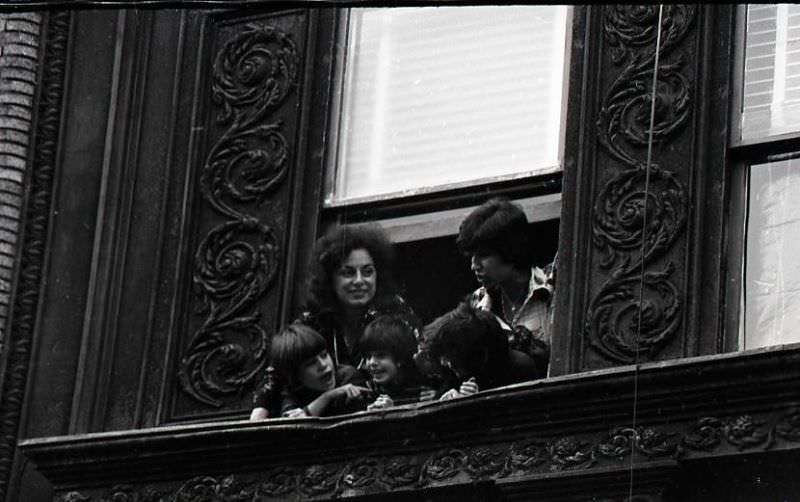 Woman and children watch North End Christmas parade from window