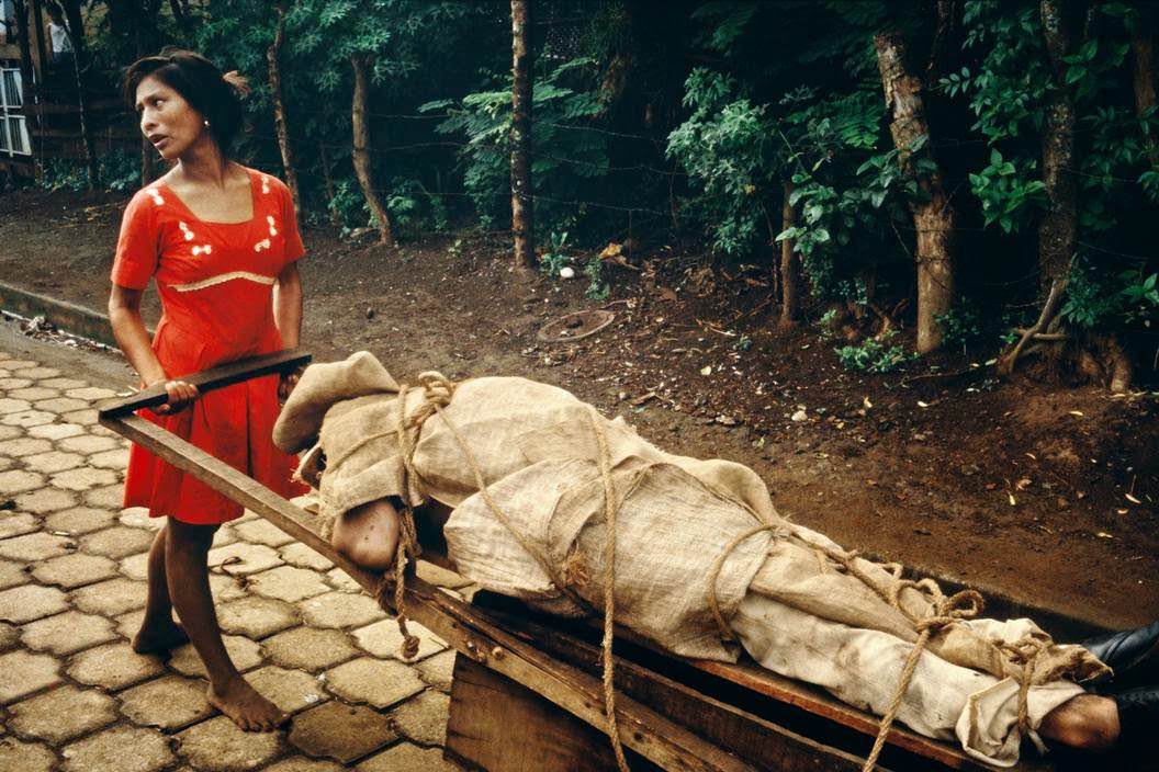 Monimbo woman carrying her dead husband home to be buried in their backyard, Monibo, 1979