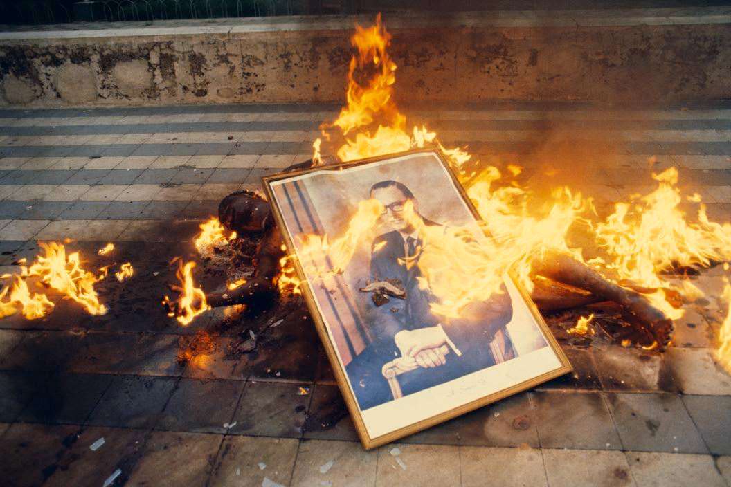 Body of National Guardsman, killed during the taking of Jinotepe, being burned with the official state portrait of President Somoza, 1979