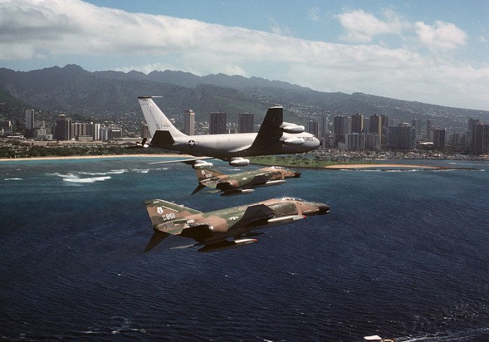 Two United States Air Force aircraft fly in formation with a Boeing KC-135A of the Arizona Air National Guard, with the Honolulu Skyline in the background.