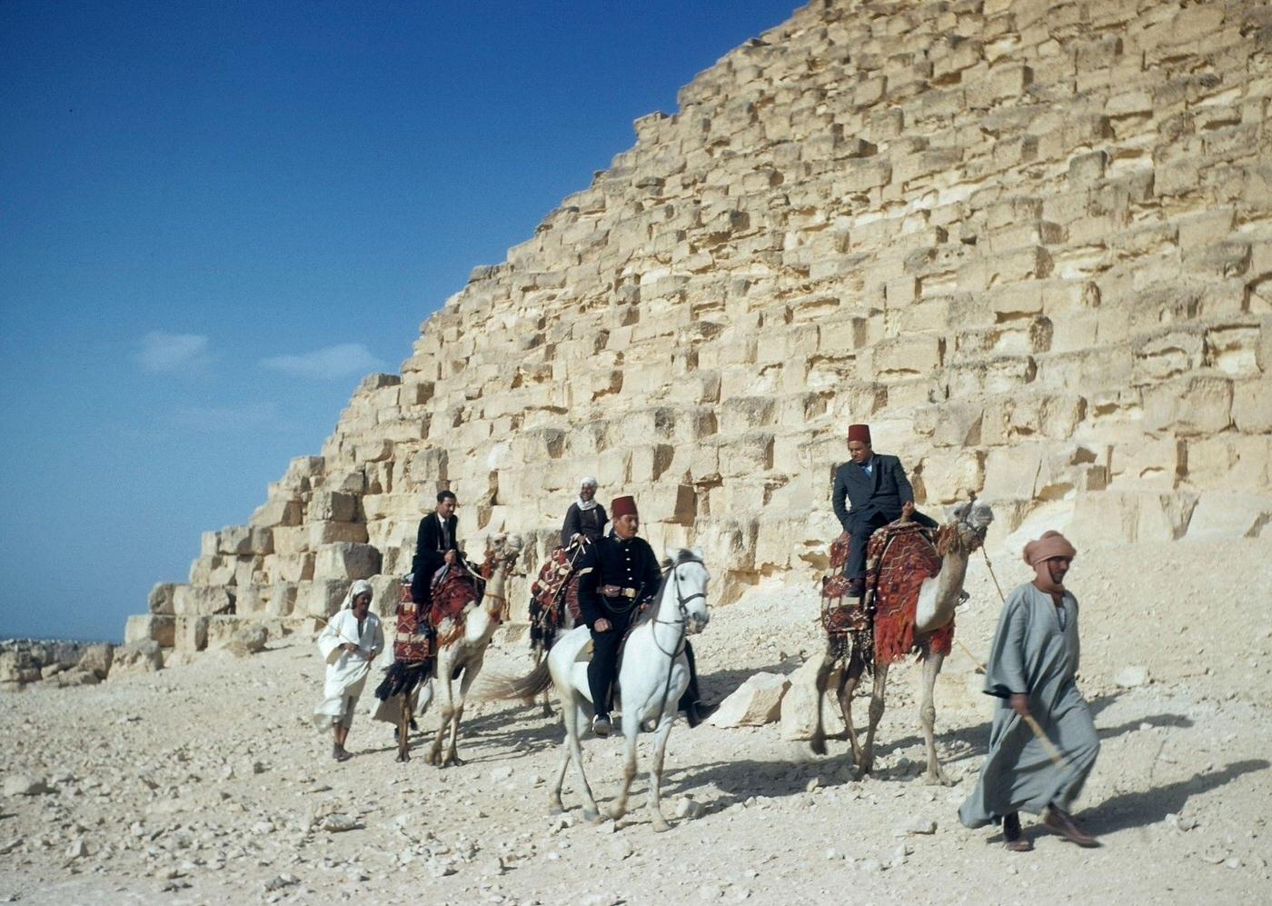 A group of men are lead by camel past the Great Pyramid of Giza (Pyramid of Khufu) in Giza, Egypt, 1940s