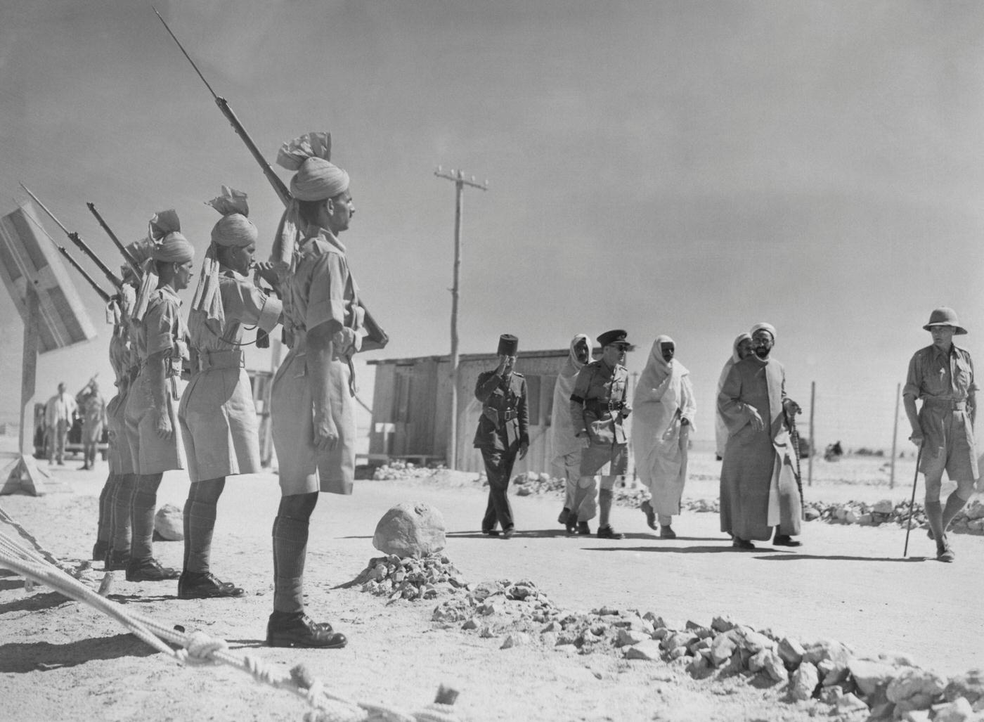 Sayyid Muhammad Idris (1889 - 1983), leader of the Free Libyans, accompanied by Senussi, British and Egyptian officers and an Indian Guard of Honour during his exile in Egypt, 1940.