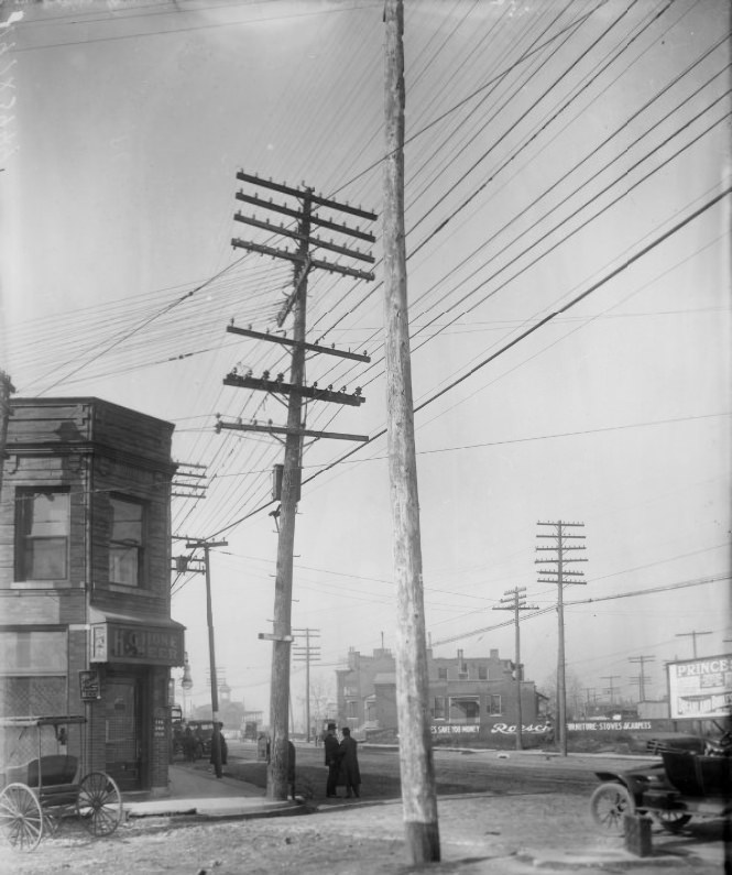 South Taylor Avenue and Manchester Avenue, 1900. A bar is visible at the corner. Two men are in a discussion in the street. An automobile is partially visible on the right.