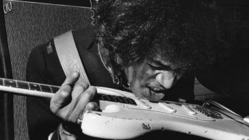 Jimi Hendrix playing guitar with teeth