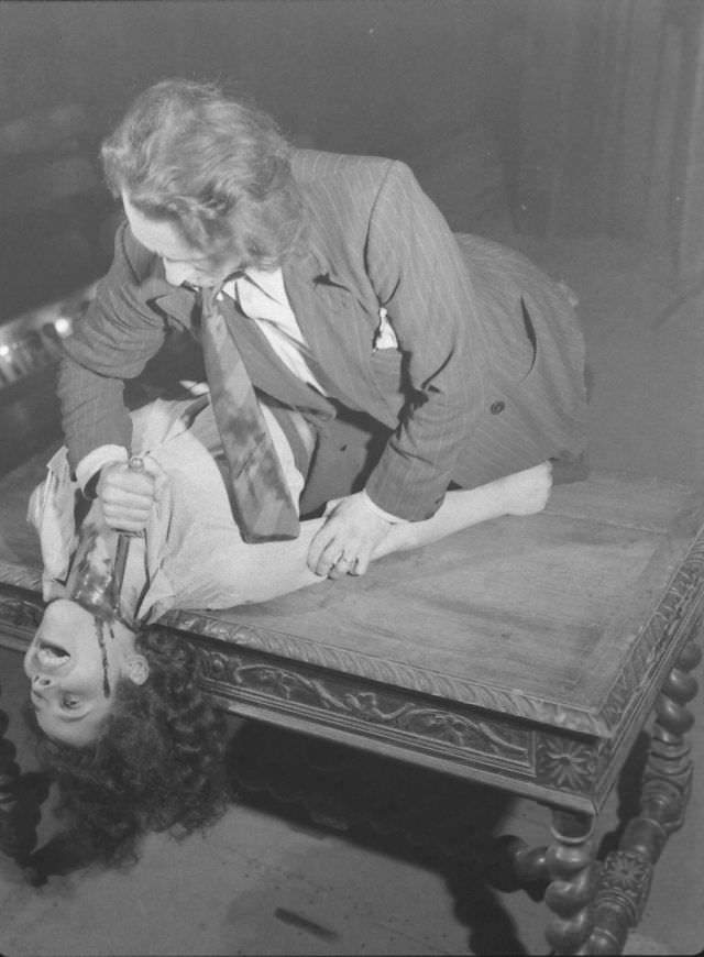 Actor dramatizing the realistic stabbing trick in production at the Grand Guignol Theater.