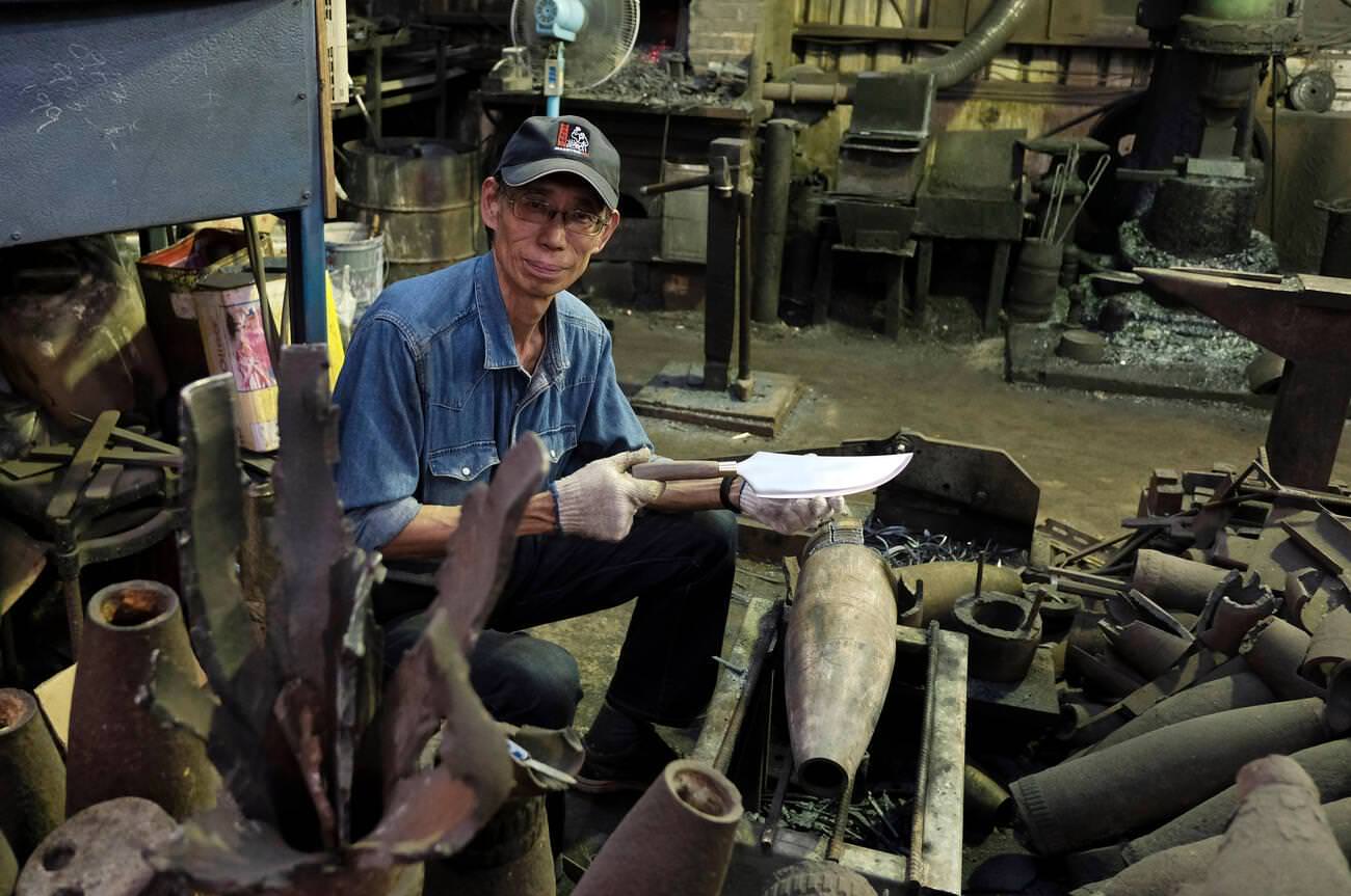 Taiwanese blacksmith Wu Tseng-tong known as Maestro Wu crafts a knife from recovered artillery shells in Kinmen County or island few miles from mainland China, Taiwan, 1950s