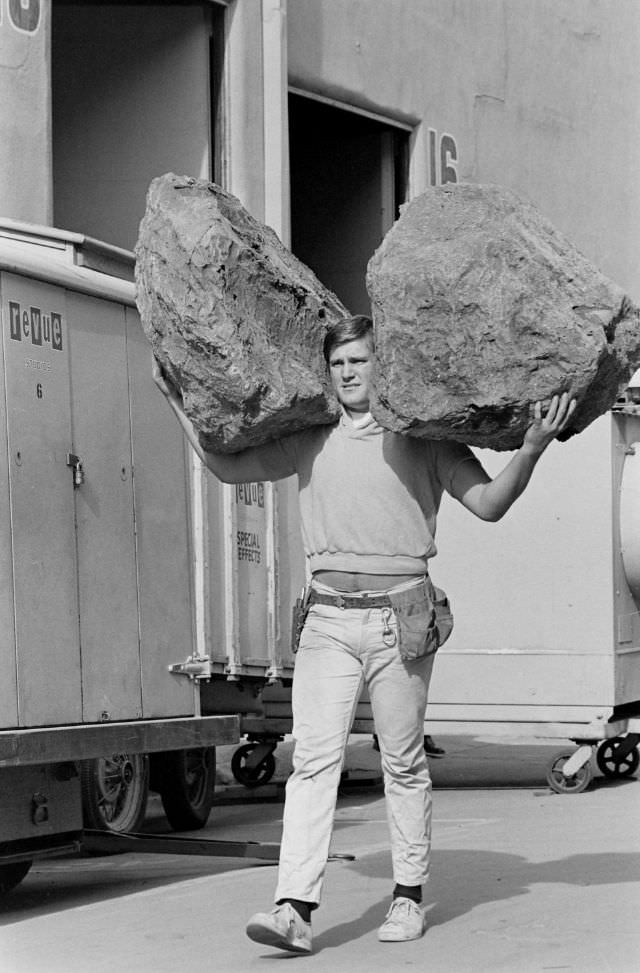 A prop man carried large rubber rocks at the Universal studio lot, Hollywood, 1963.