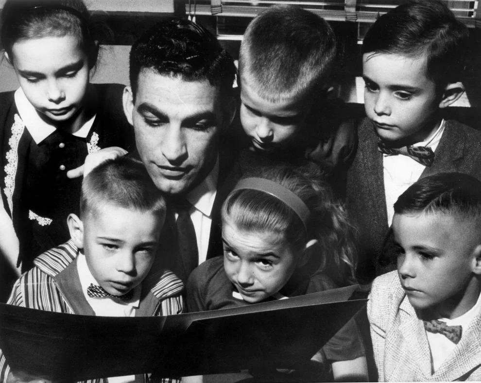 Richmond Newspapers photographer Amir Pishdad (center) reviewed his naturalization certificate with six children who became American citizens along with him that day, 1960.