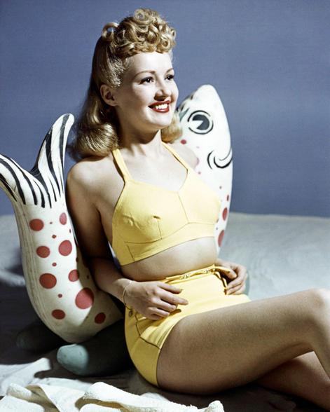 Betty Grable, nữ diễn viên người Mỹ, trong bộ bikini màu vàng dựa vào vật trang trí hình con cá, năm 1940.