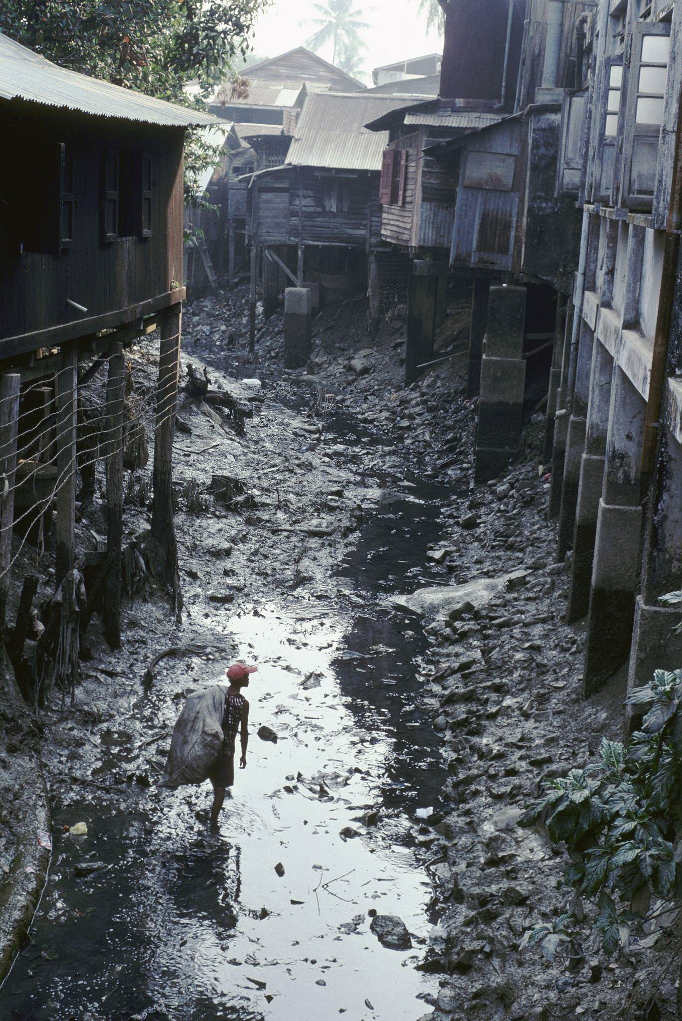 Myanmar - Young Child Gathering Rubbish in Canal in Moulmein, 1980s