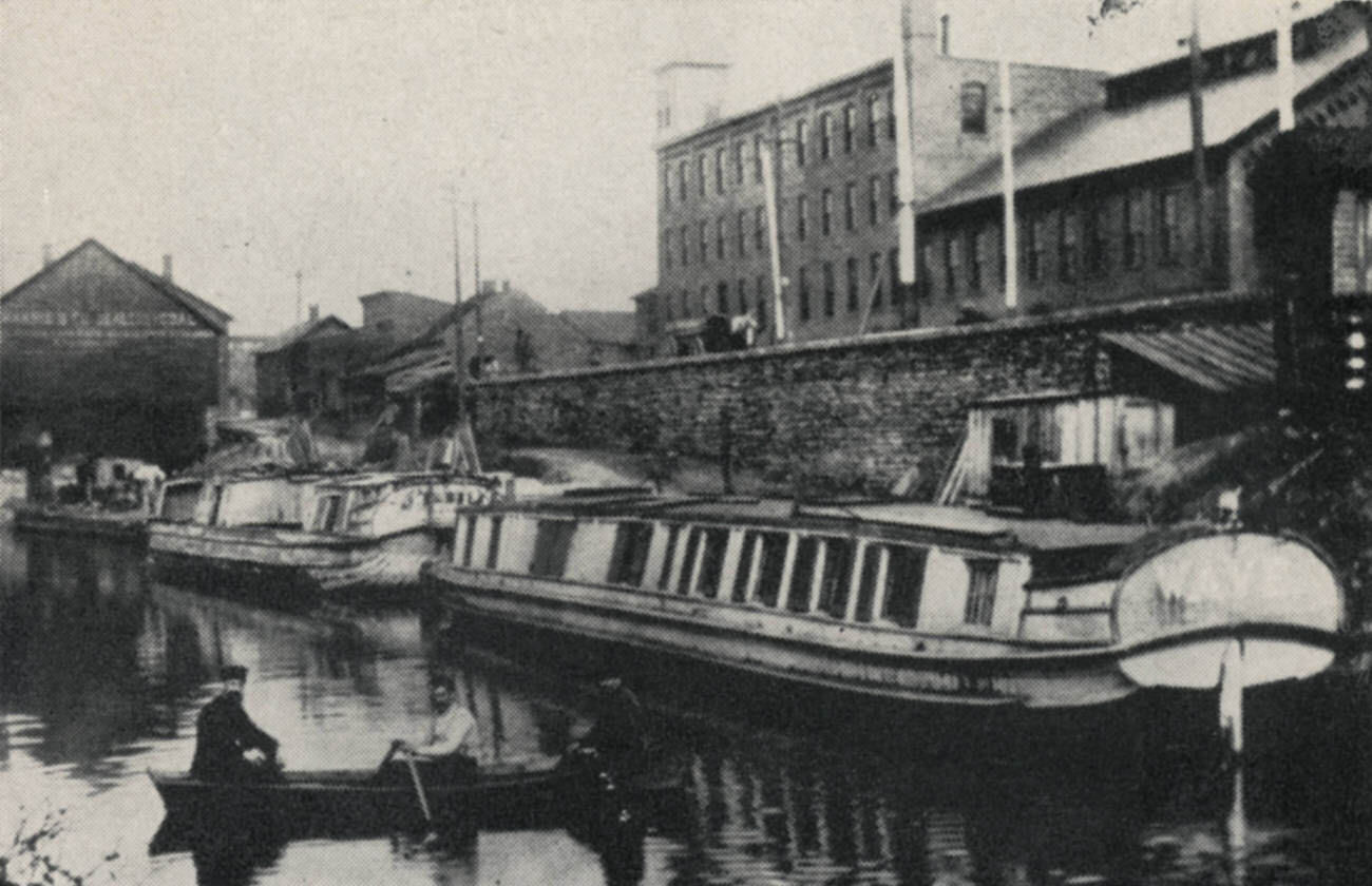 Canal boats and warehouses near Main Street, Jackson-Guldan Violin Company in the background, 1954.