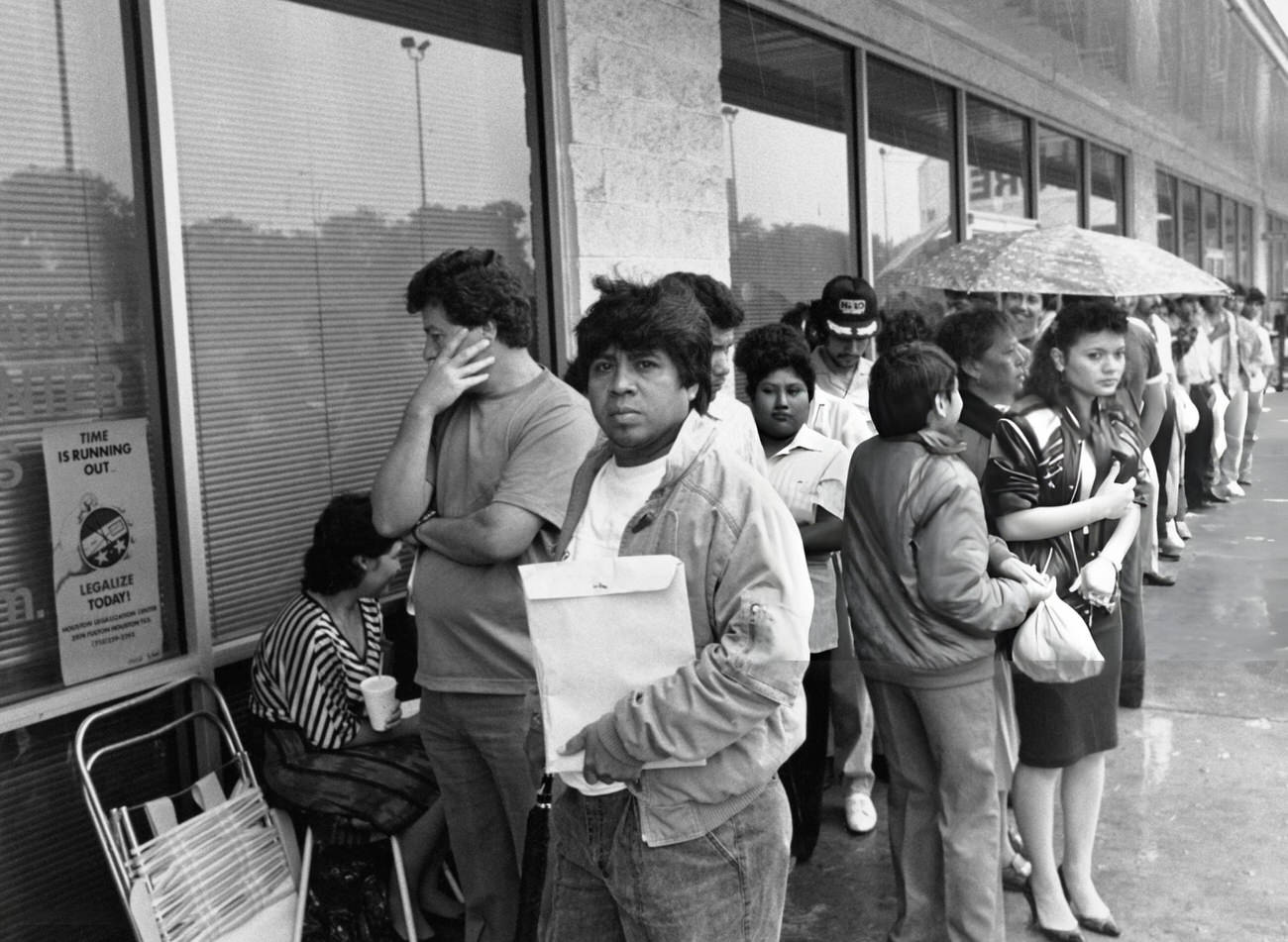 U.S. citizens wait in the rain outside the Immigration and Naturalisation Service, Houston, Texas, April 29, 1988.