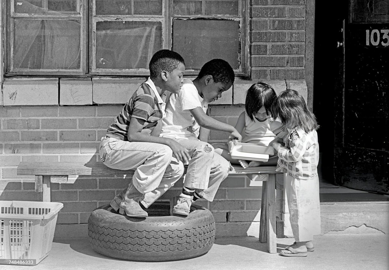 Two African American boys play with two Asian immigrant girls, Houston, Texas, 1983.