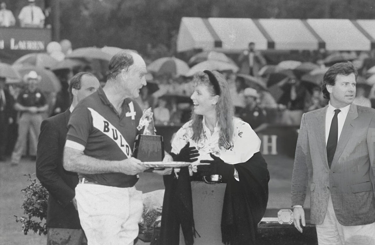 Sarah Ferguson stands in the rain on a polo field with her father, Major Ronald Ferguson, during her visit to Houston, Texas.