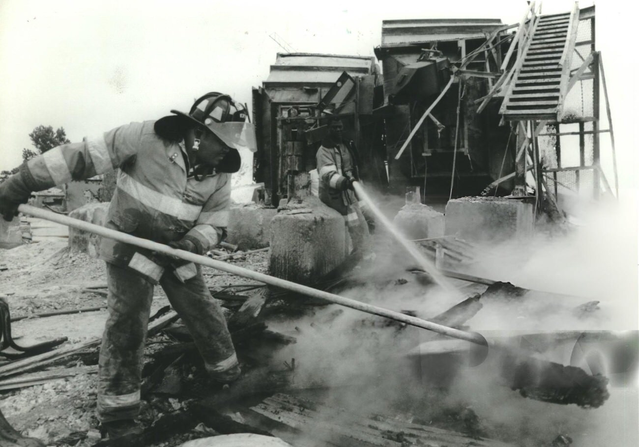 Firefighters combat a blaze at the defunct South Post Oak Glass Company, highlighting old timbers and debris burning, Houston.