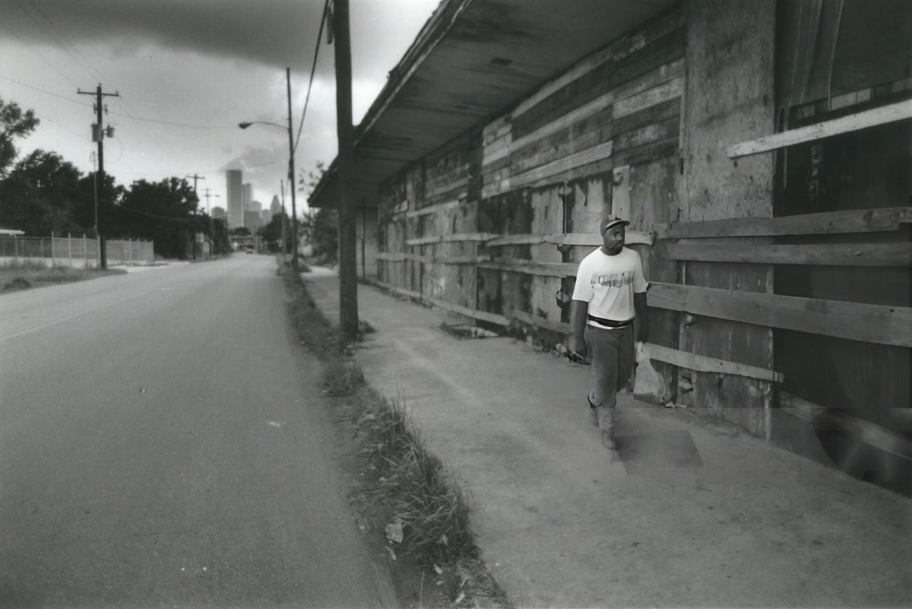 Horace Wilson's walk past boarded-up storefronts on Lyons Avenue illustrates the decline of once-vibrant business districts in Houston's Fifth Ward.