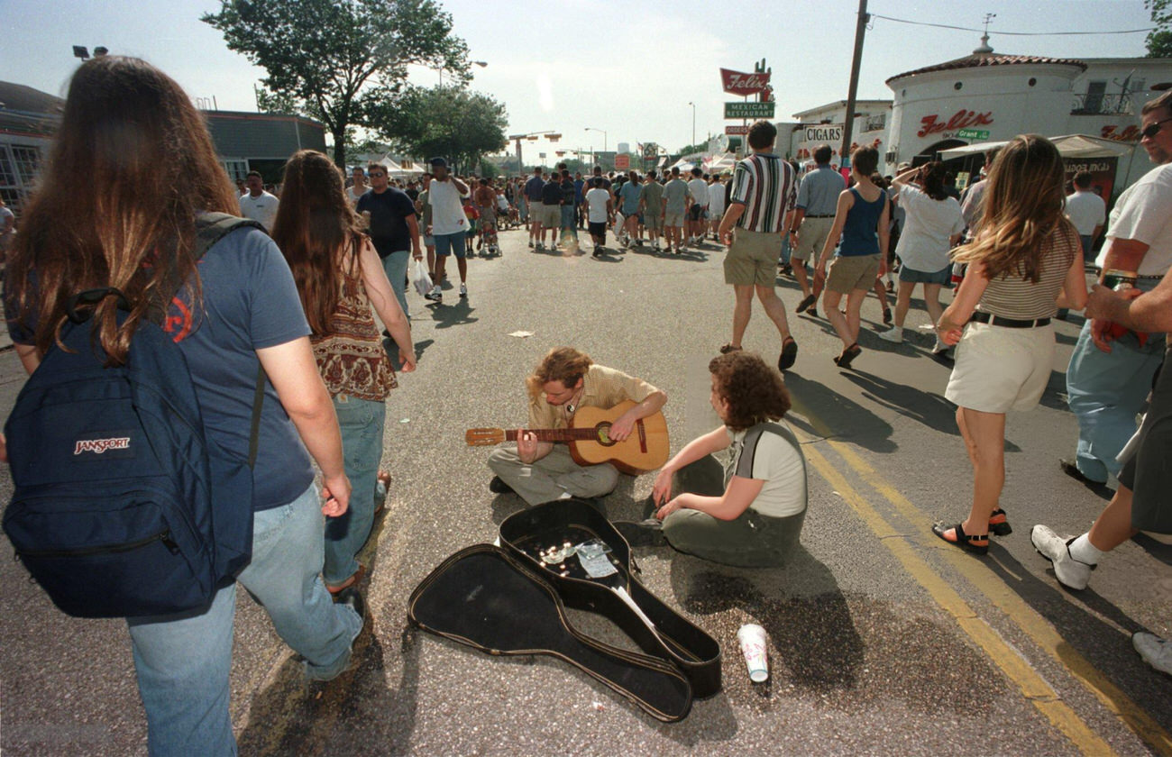Patrick Napier and Melissa Garrett play guitar amid the crowd at the Westheimer Street Festival, Houston, Texas, 1998.