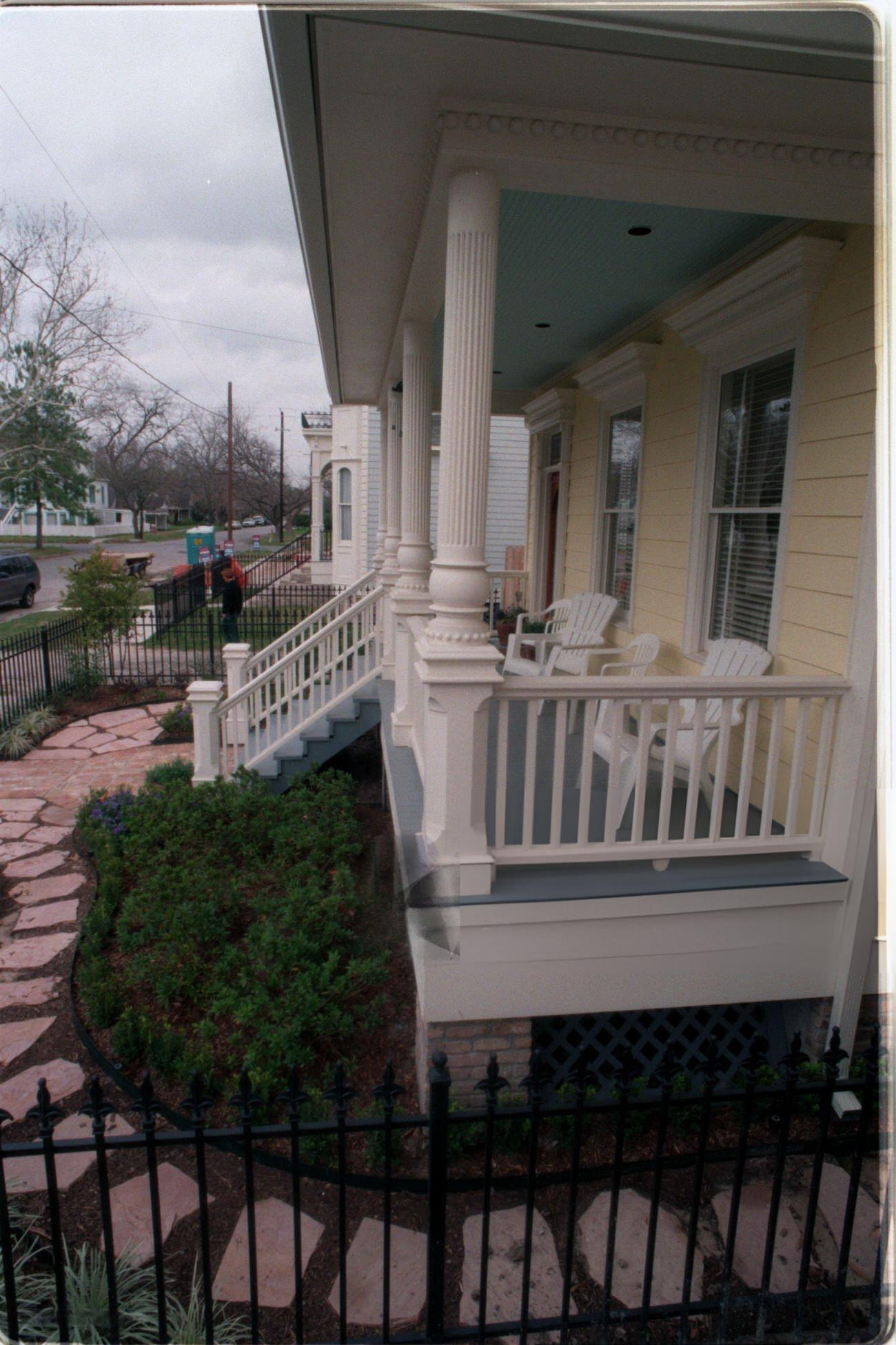 Home construction showcases wicker furniture and iron fence in the Houston Heights with rising median prices, 1998.
