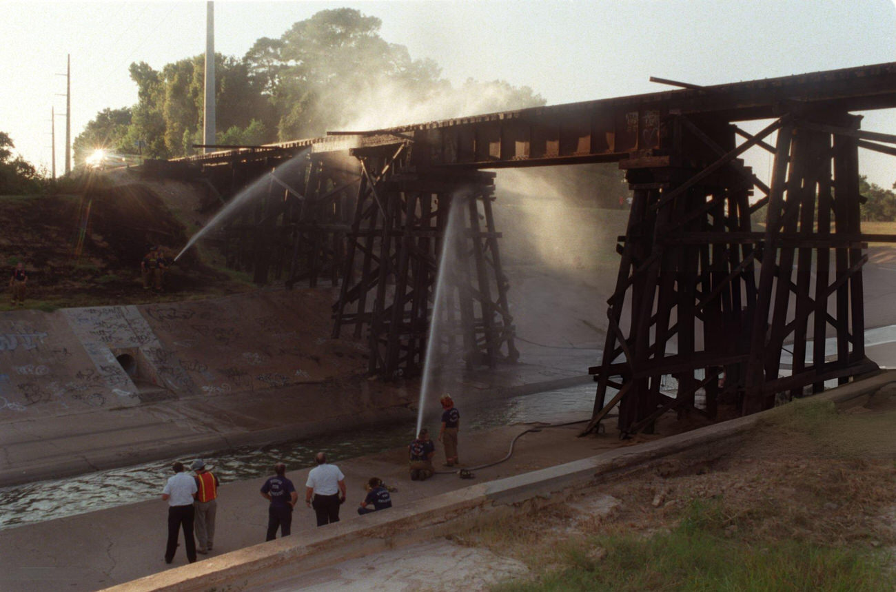 Firefighters douse a burning railroad trestle over White Oak Bayou, Houston, Texas, 1999.