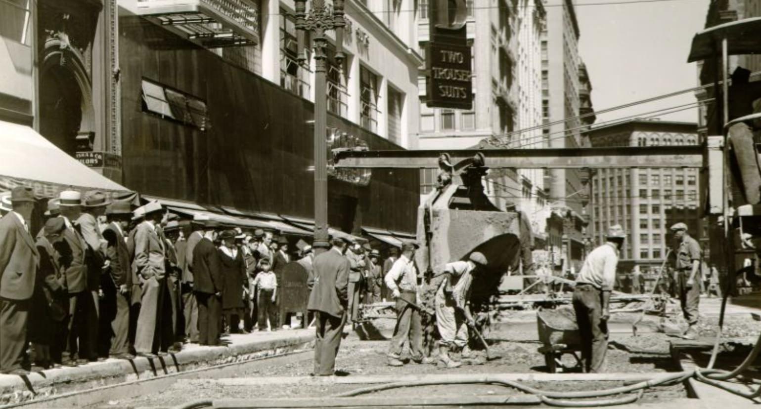 Spectators watching work crew mixing cement at Post and Kearny streets, 1940