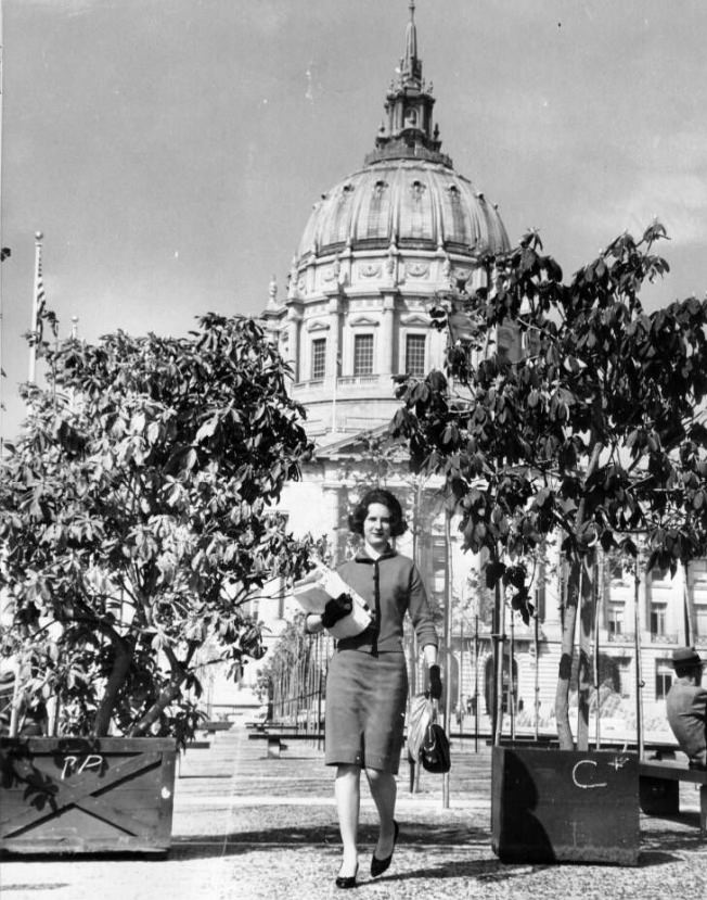 Candis Smyk walking by rhododendron planters in Civic Center Plaza, 1962.