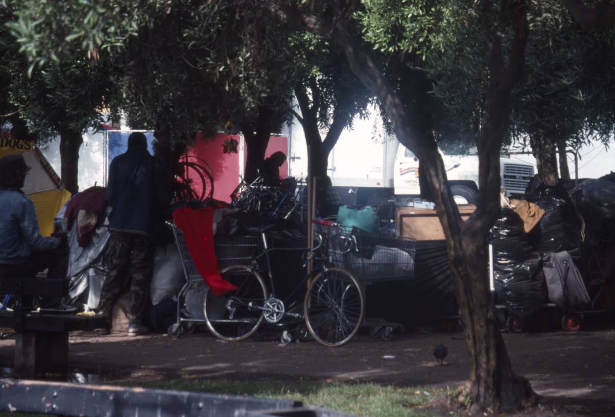 People with belongings in plastic bags and carts at Civic Center Plaza, 1989.